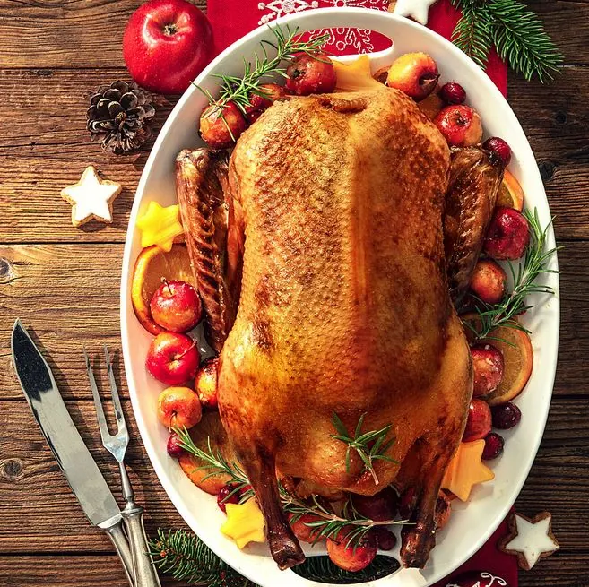 Gebratene Gans auf einer Platte mit Äpfeln und Rosmarin