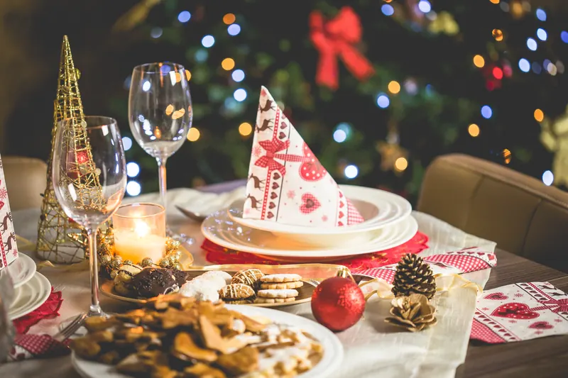 Festlich gedeckter Weihnachtstisch mit Lichterkette, Gläsern und Gebäck
