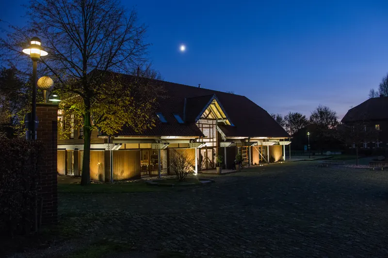 Das Clubhaus mit dem Restaurant UNVERHOFFT am Abend, warm beleuchtet