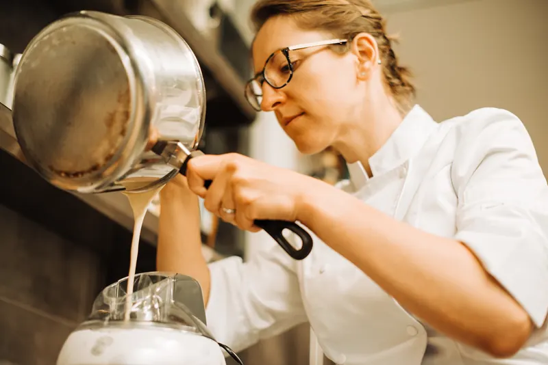 Köchin gießt in der Küche Sauce aus einem Topf